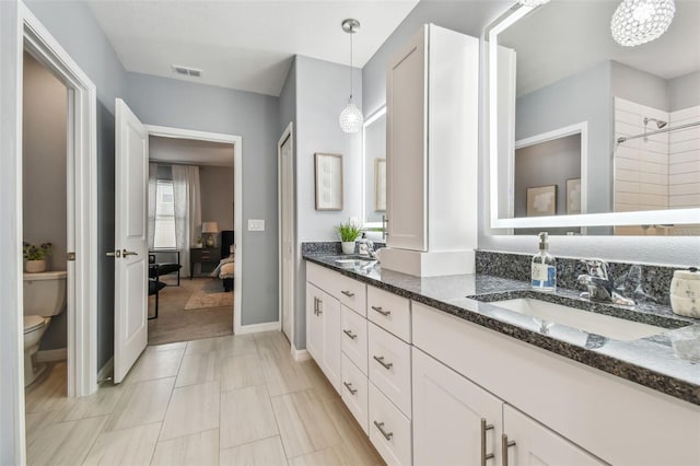 ensuite bathroom with double vanity, toilet, visible vents, and a sink