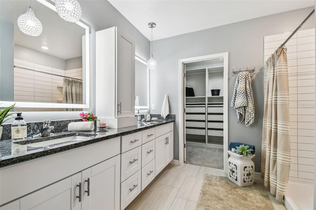 full bathroom featuring a sink, double vanity, and a tile shower