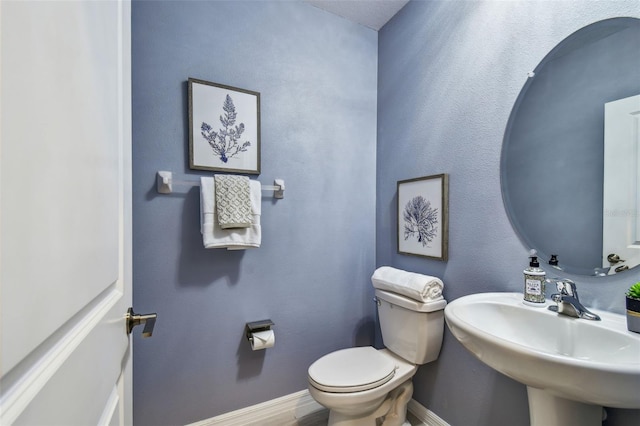 bathroom featuring toilet, baseboards, and a sink