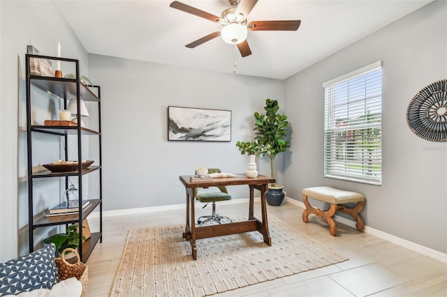 office space with baseboards and ceiling fan