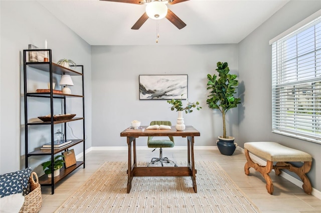 office space featuring a ceiling fan, a healthy amount of sunlight, and light wood finished floors