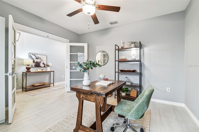 home office with visible vents, light wood-style flooring, a ceiling fan, and baseboards