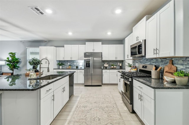 kitchen with visible vents, decorative backsplash, appliances with stainless steel finishes, white cabinetry, and a sink