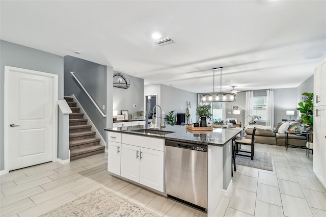 kitchen with visible vents, dark stone counters, a sink, dishwasher, and open floor plan