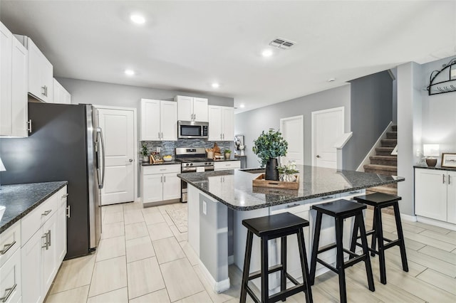 kitchen with visible vents, a center island, a kitchen bar, decorative backsplash, and stainless steel appliances