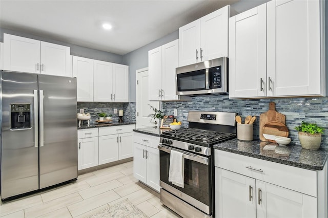 kitchen with dark stone counters, tasteful backsplash, appliances with stainless steel finishes, and white cabinetry