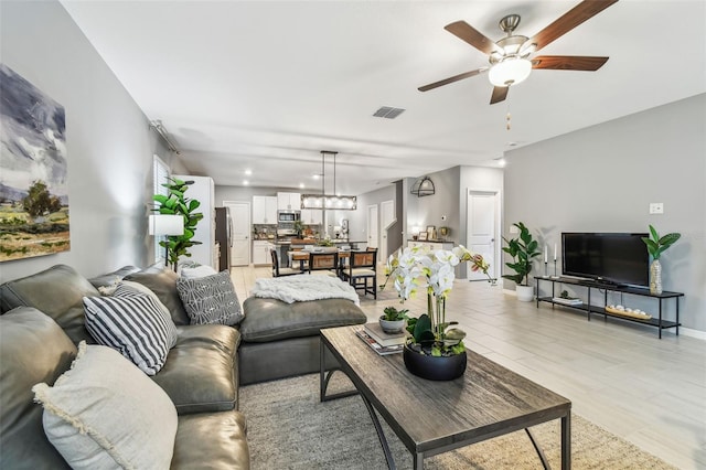 living area featuring visible vents, baseboards, and a ceiling fan