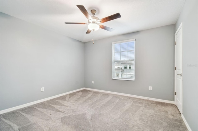 carpeted empty room featuring ceiling fan and baseboards