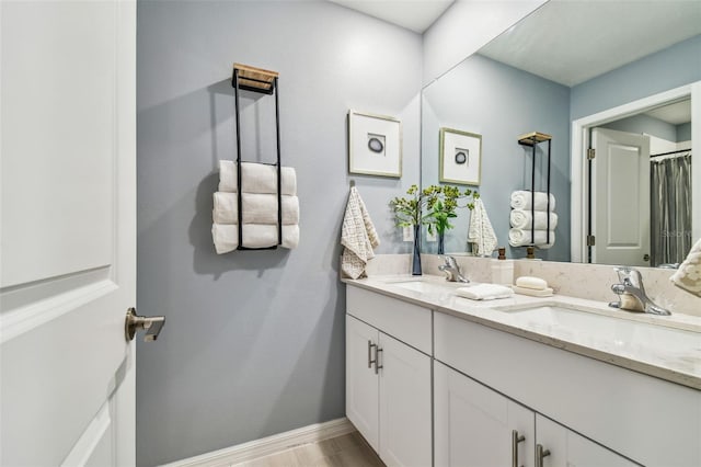 bathroom with a sink, baseboards, and double vanity