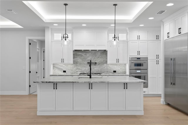 kitchen with appliances with stainless steel finishes, a raised ceiling, visible vents, and white cabinetry