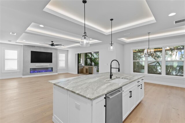 kitchen with light wood finished floors, visible vents, a raised ceiling, dishwasher, and a sink