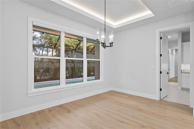 unfurnished dining area with baseboards, a notable chandelier, and light wood-style floors