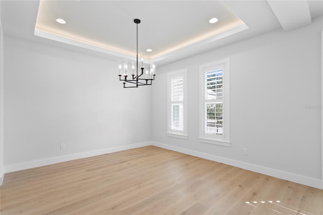 empty room featuring a raised ceiling and baseboards