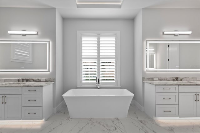 full bath featuring marble finish floor, two vanities, and a freestanding bath