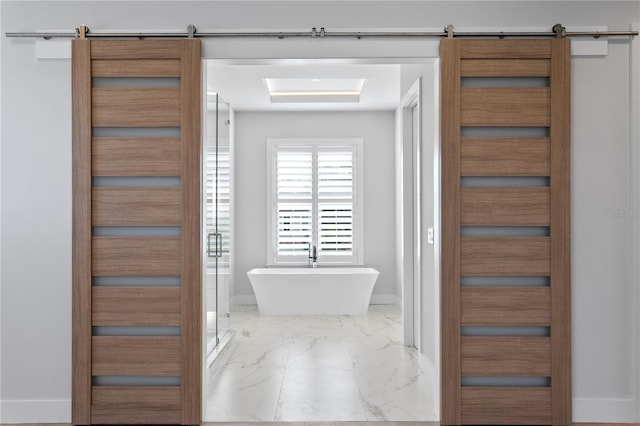 bathroom featuring a freestanding bath, marble finish floor, and baseboards