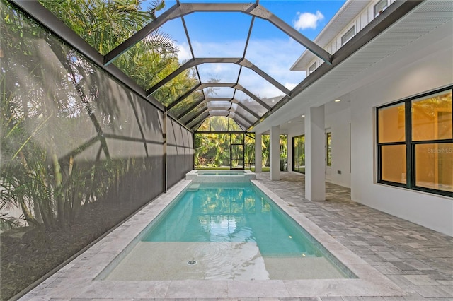 view of swimming pool with glass enclosure, a patio area, and a pool with connected hot tub