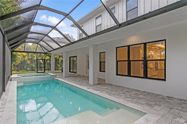 view of pool featuring a pool with connected hot tub, glass enclosure, and a patio