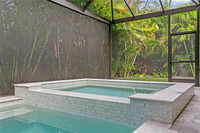 view of swimming pool featuring glass enclosure and an in ground hot tub