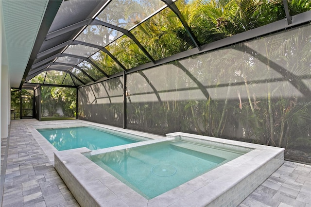 view of swimming pool featuring a lanai, a pool with connected hot tub, and a patio