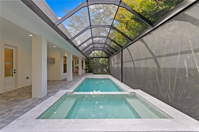 view of swimming pool featuring a patio area, a pool with connected hot tub, and glass enclosure