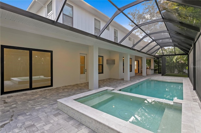 view of swimming pool featuring glass enclosure, a patio area, and a pool with connected hot tub