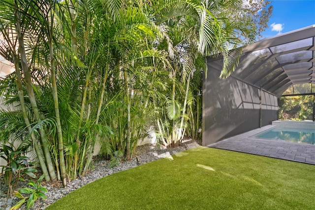 view of yard with glass enclosure, an outdoor pool, and a patio