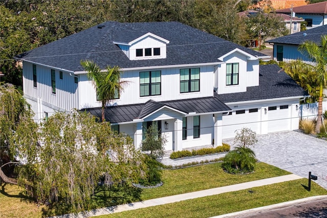 modern inspired farmhouse with a garage, a shingled roof, decorative driveway, a standing seam roof, and a front yard