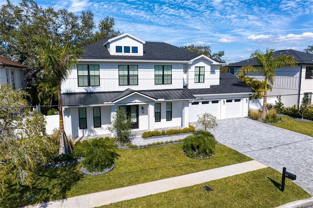 view of front of home with an attached garage, fence, decorative driveway, a standing seam roof, and a front yard