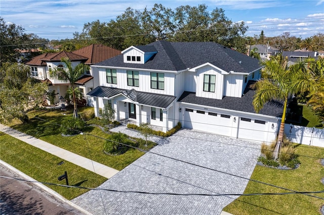 modern inspired farmhouse featuring a front lawn, roof with shingles, an attached garage, and decorative driveway