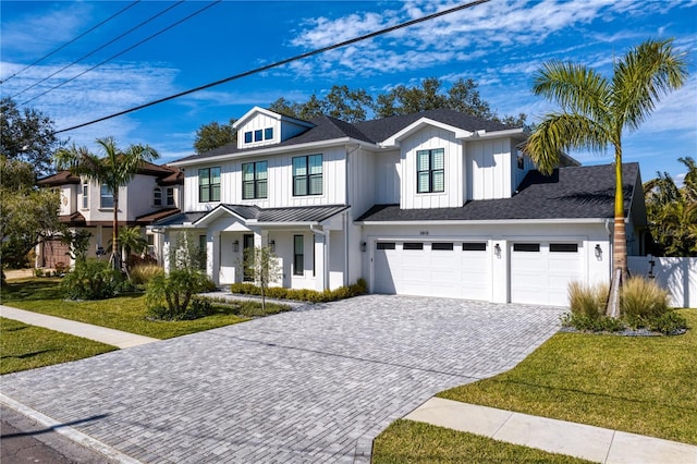 modern farmhouse with a garage, decorative driveway, and a front yard