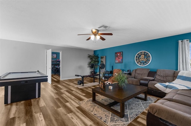 living room with baseboards, wood finished floors, visible vents, and a ceiling fan