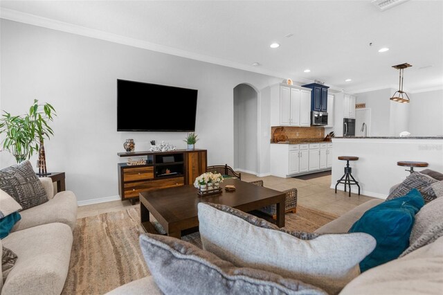 living area with arched walkways, crown molding, baseboards, and recessed lighting