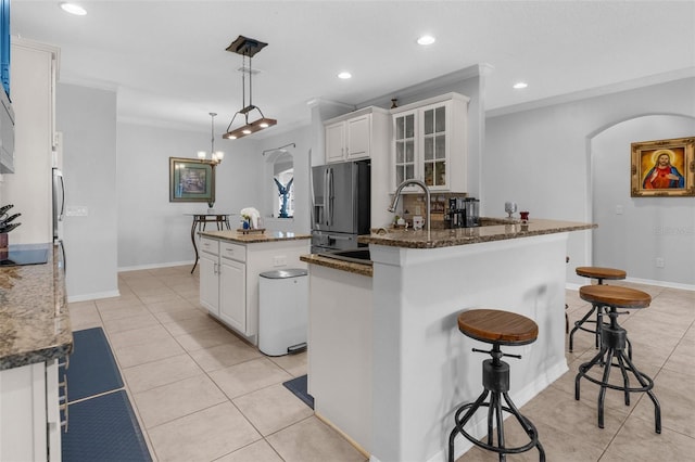 kitchen featuring light tile patterned flooring, stainless steel fridge, arched walkways, and ornamental molding