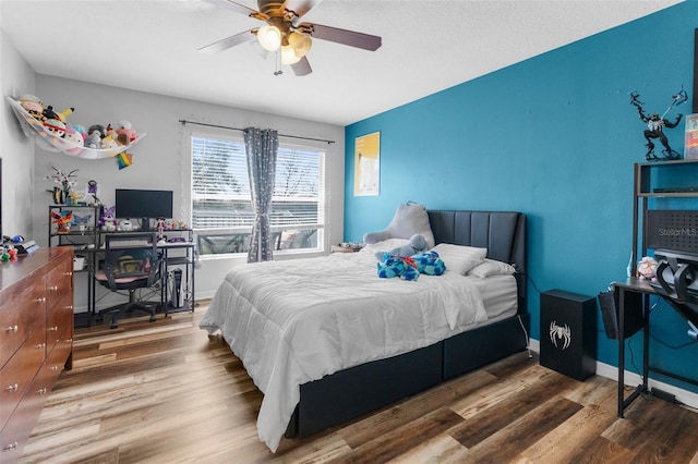 bedroom featuring a ceiling fan, baseboards, and wood finished floors