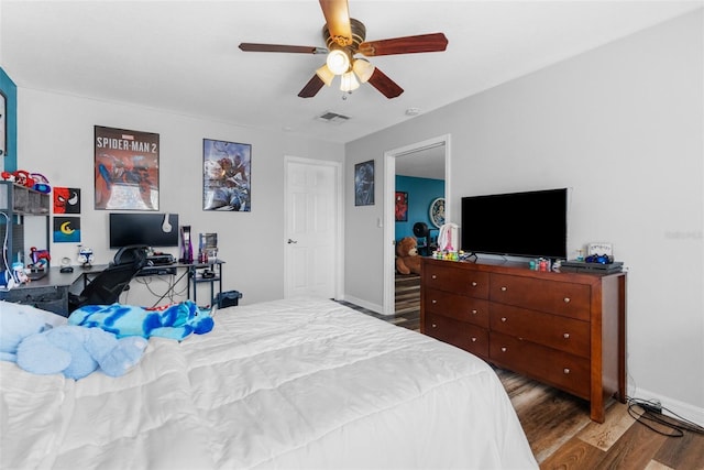 bedroom featuring baseboards, ceiling fan, visible vents, and wood finished floors