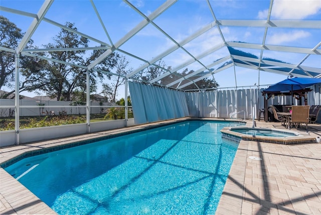 view of pool featuring a patio area, a pool with connected hot tub, and glass enclosure