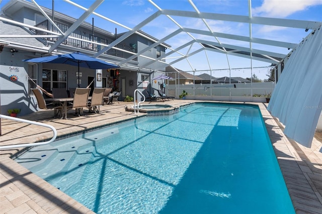 view of pool with a lanai, a pool with connected hot tub, fence, and a patio