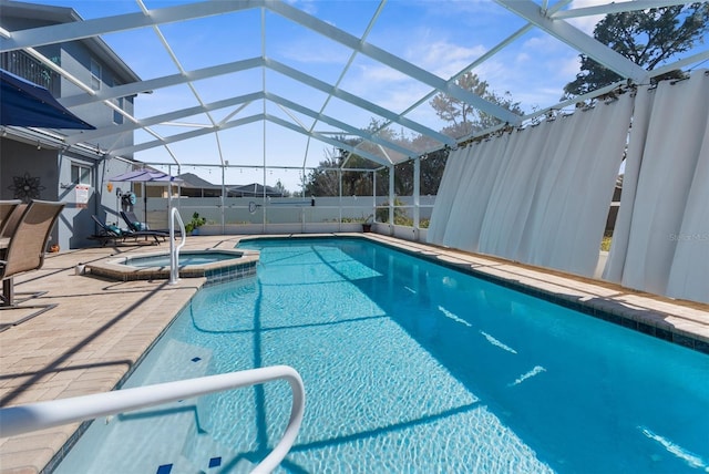 view of pool with a pool with connected hot tub, glass enclosure, fence, and a patio