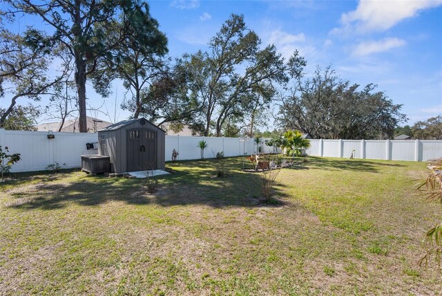 view of yard featuring a fenced backyard, a storage unit, and an outbuilding