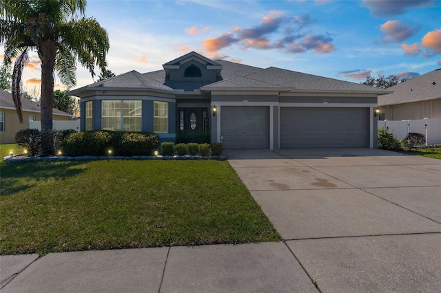 view of front of property with an attached garage, a front lawn, concrete driveway, and stucco siding