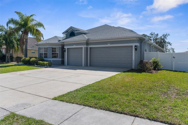 ranch-style home featuring an attached garage, fence, concrete driveway, stucco siding, and a front lawn