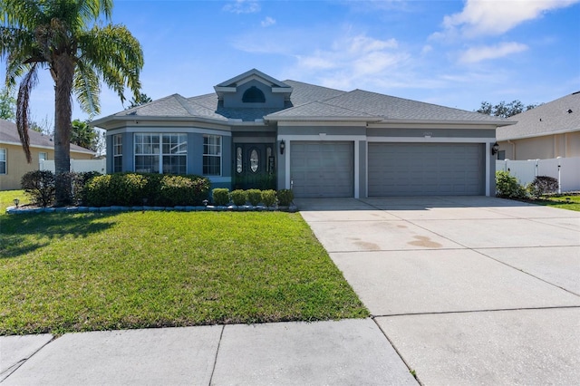 view of front of house featuring a front yard, driveway, an attached garage, and stucco siding