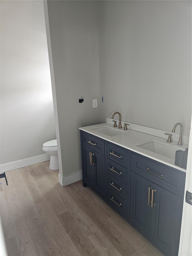 full bath featuring a sink, baseboards, toilet, and wood finished floors