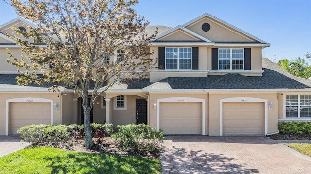 view of front of home featuring driveway, roof with shingles, and stucco siding