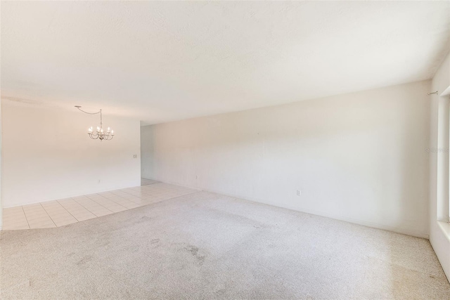 tiled empty room with carpet flooring and an inviting chandelier