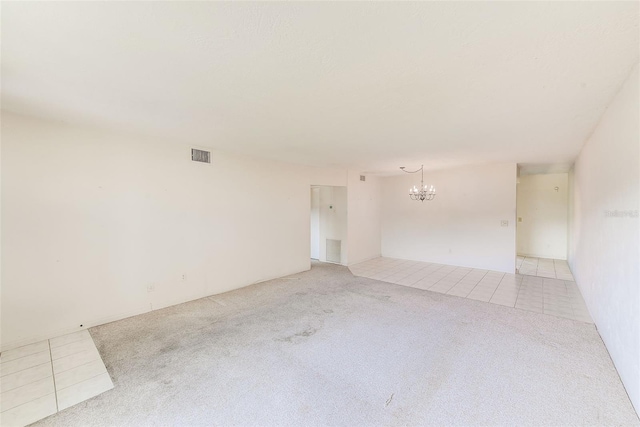 tiled spare room with carpet flooring, visible vents, and an inviting chandelier