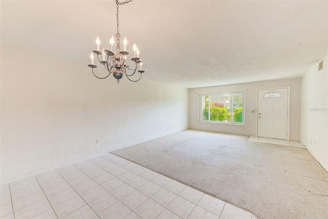 unfurnished room with light carpet and an inviting chandelier