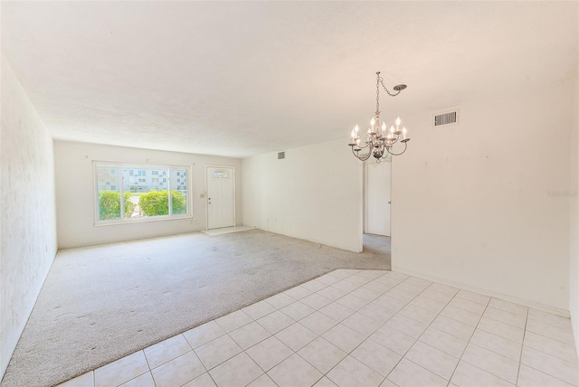 spare room with light carpet, visible vents, and a chandelier