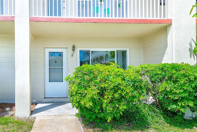 view of exterior entry featuring concrete block siding and a balcony