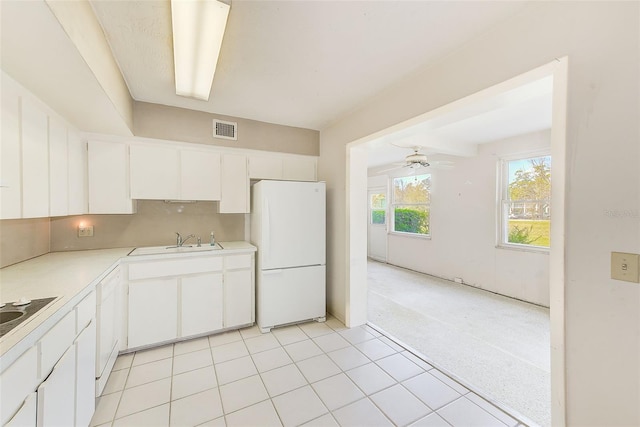 kitchen featuring visible vents, freestanding refrigerator, light countertops, white cabinetry, and a sink